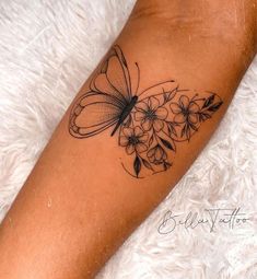 a woman's leg with a butterfly and flowers tattoo on the left side of her arm