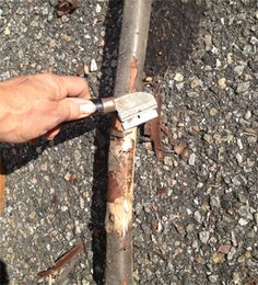 a man is holding a wrench to the side of a metal pipe that has been bent over