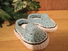 a pair of crocheted slippers sitting on top of a wooden table next to a potted plant