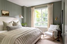 a bedroom with a bed, chair and window in the corner is decorated in pale colors