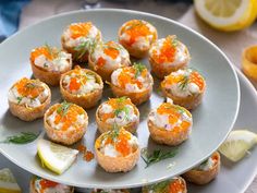 small appetizers are arranged on a plate with lemon wedges