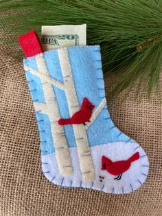 a christmas stocking hanging from a tree with two red birds perched on the branch