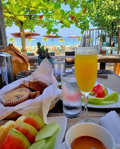 an outdoor dining area with fruit, watermelon and muffins on the table