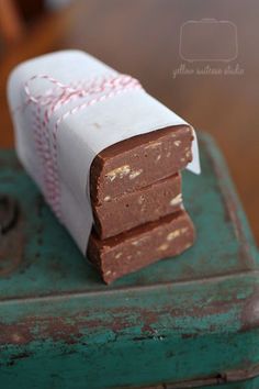 three pieces of chocolate sitting on top of a green box with red and white string