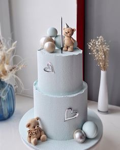 a three tiered cake with teddy bears on top and decorations around the bottom layer