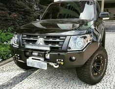 a black truck parked on top of a cobblestone road