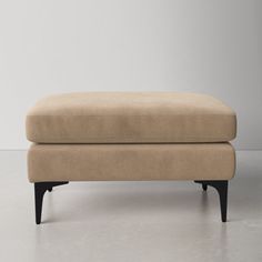 a beige footstool sitting on top of a white floor next to a wall