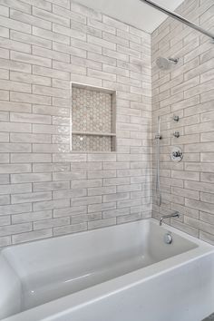 a white bath tub sitting inside of a bathroom next to a shower head and hand rail