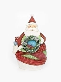 a santa clause figurine sitting on top of a pile of yarn