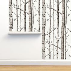 the wallpaper is white and has black trees on it, along with a wooden floor