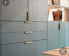 the cabinets are made of wood and have brass knobs on each drawer, along with bookshelves