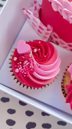 two cupcakes with pink frosting and hearts on them