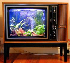 an old fashioned television set with fish in it's tank sitting on top of a wooden stand