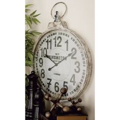 an alarm clock sitting on top of a shelf next to a potted plant and books