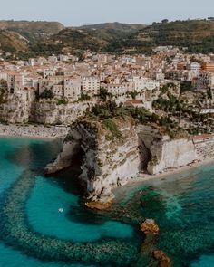 an aerial view of the city and its surrounding cliffs, with clear blue water in front