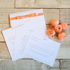 three envelopes and some flowers on top of a wooden table with wood planks