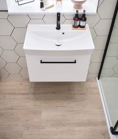 a bathroom sink sitting under a mirror next to a walk in shower and toiletries