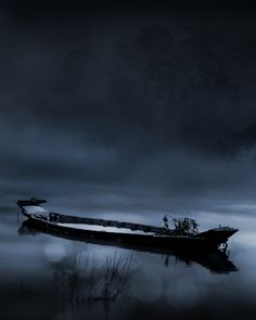 a boat floating on top of a body of water under a dark sky with clouds