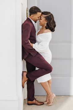 a man in a suit and tie leaning against a wall next to a pregnant woman