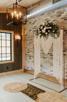 a wedding ceremony setup with macrami and flowers on the back wall, hanging from a chandelier