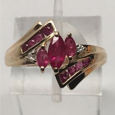 a gold ring with pink and white stones on it's sides, sitting in a clear display case