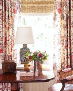 a living room filled with furniture next to a window covered in curtains and drapes