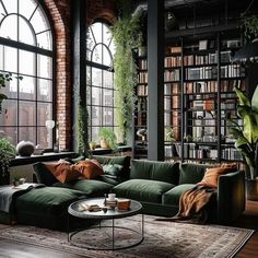 a living room filled with lots of green furniture and bookshelves next to large windows