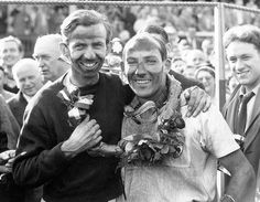 black and white photograph of two men smiling for the camera with people in the background