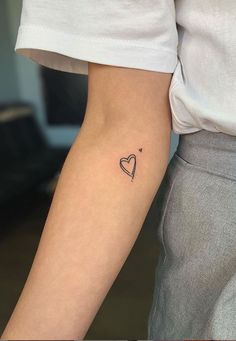 a woman's arm with a small heart tattoo on the left side of her arm