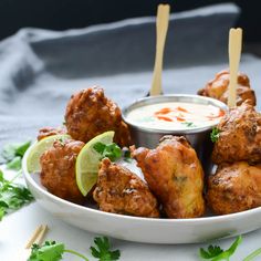 a white plate topped with meatballs and dip next to cilantro wedges