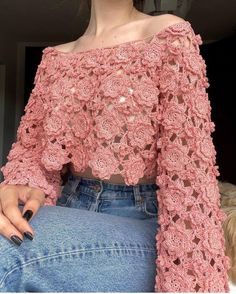 a woman wearing a pink crochet top and jeans