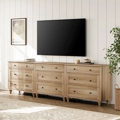 a large flat screen tv mounted to the side of a wooden dresser in a living room