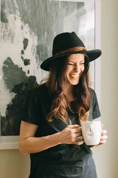 a woman wearing a black hat and holding a coffee cup