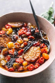 a bowl filled with meat and vegetables on top of a white counter next to a spoon