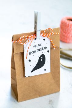 a brown paper bag with a black ghost tag hanging from it's side on a table