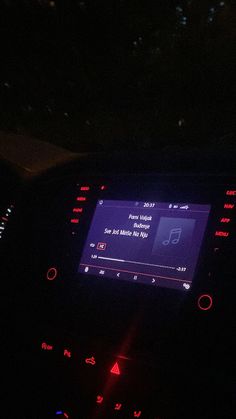 a car dashboard with an electronic screen showing music