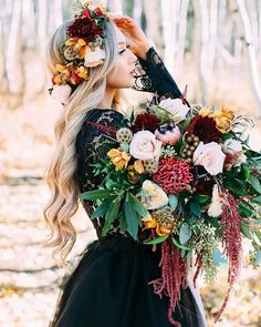 a woman with long blonde hair wearing a black dress and holding a bouquet