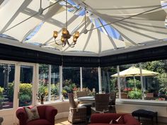 a living room filled with furniture and lots of windows next to a table covered in umbrellas