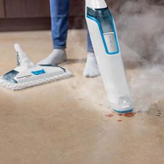 a person is using a steam mop to clean the floor in front of them