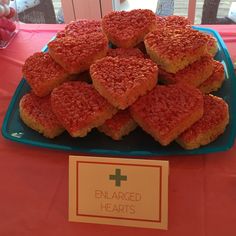 a blue plate topped with heart shaped cookies on top of a red cloth covered table