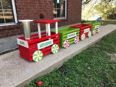 a red and green train sitting on top of a cement slab next to a brick building