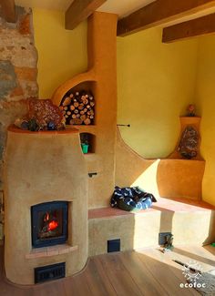 an outdoor fireplace in the middle of a room with yellow walls and wood flooring