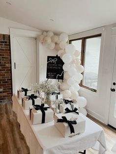 the table is set up with white balloons and gift boxes for guests to take home