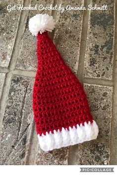 a red and white crocheted santa hat sitting on top of a tile floor