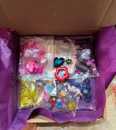 a box filled with lots of different types of buttons and beads on top of a purple cloth