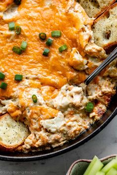 a casserole dish with bread, cheese and green onion garnishes