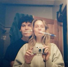 two people are taking a selfie in the mirror with toothbrushes on their mouths