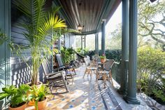 a porch with chairs and potted plants on it