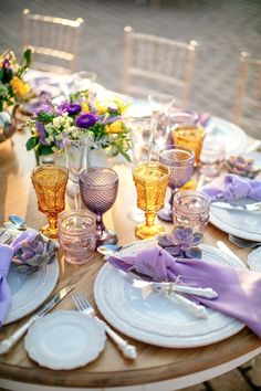 the table is set with purple and yellow dishes, silverware, and napkins