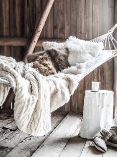 a white hammock hanging from a wooden wall next to a pair of slippers